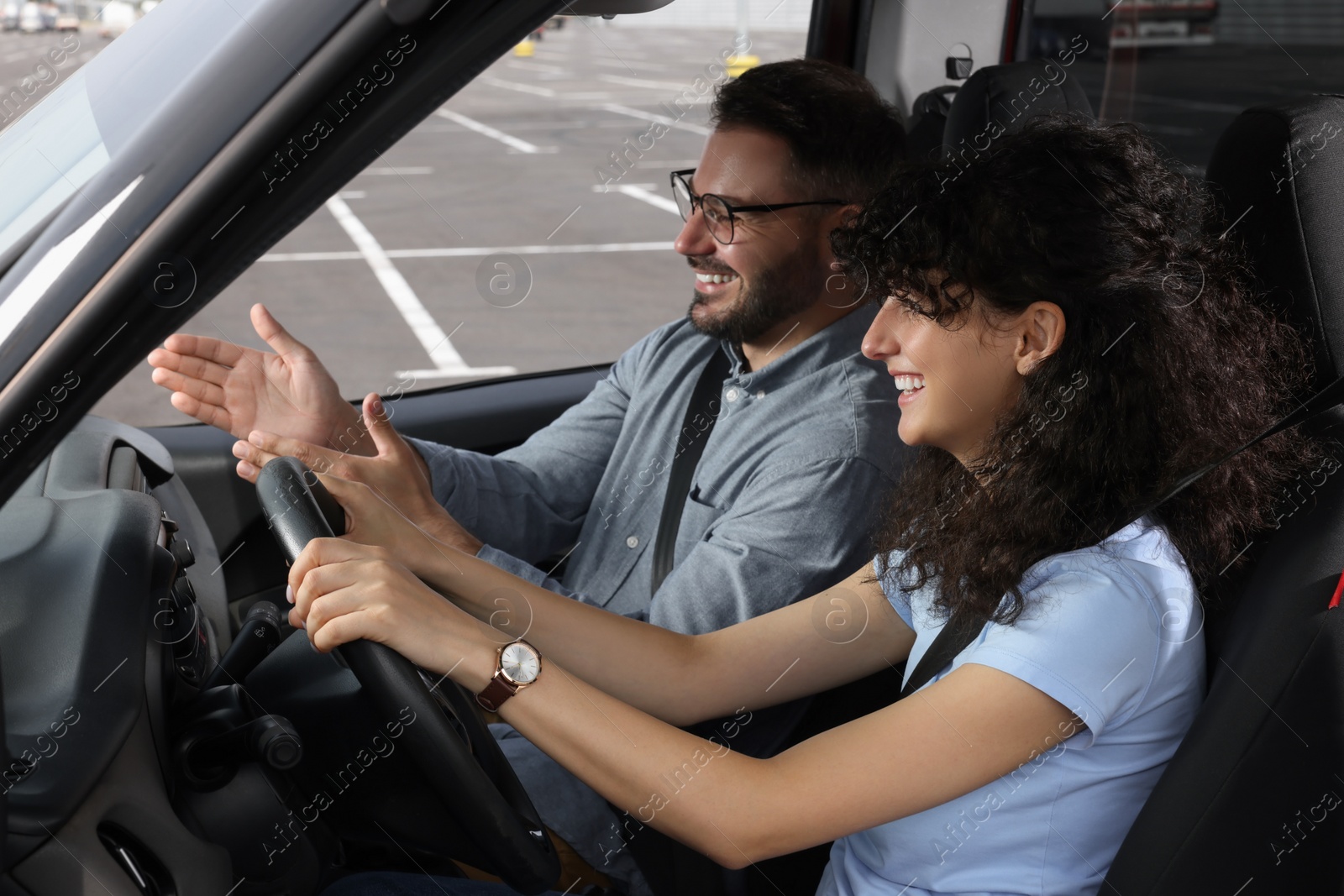 Photo of Driving school. Happy student during lesson with driving instructor in car at parking lot