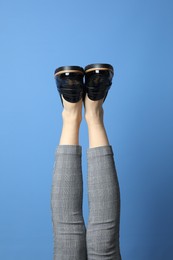 Photo of Woman wearing stylish shoes on blue background, closeup