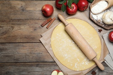 Photo of Flat lay composition with raw dough and ingredients on wooden table, space for text. Baking apple pie