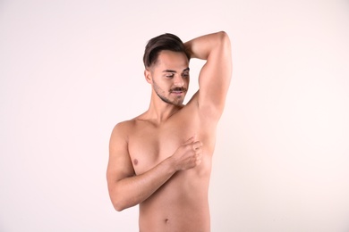 Photo of Handsome young man showing armpit on white background. Using deodorant