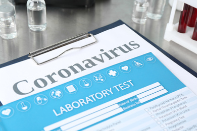 Clipboard with laboratory test list and word CORONAVIRUS on grey table, closeup