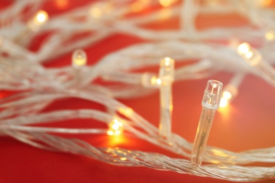 Photo of Glowing Christmas lights on color background, closeup