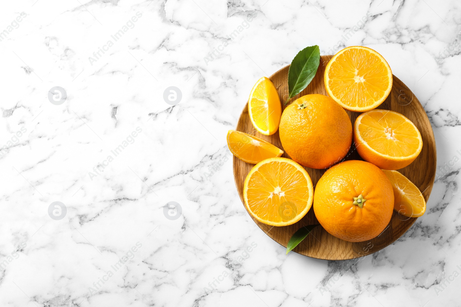 Photo of Plate with ripe oranges on marble background, top view. Space for text