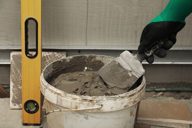 Photo of Worker taking adhesive mix with spatula, closeup