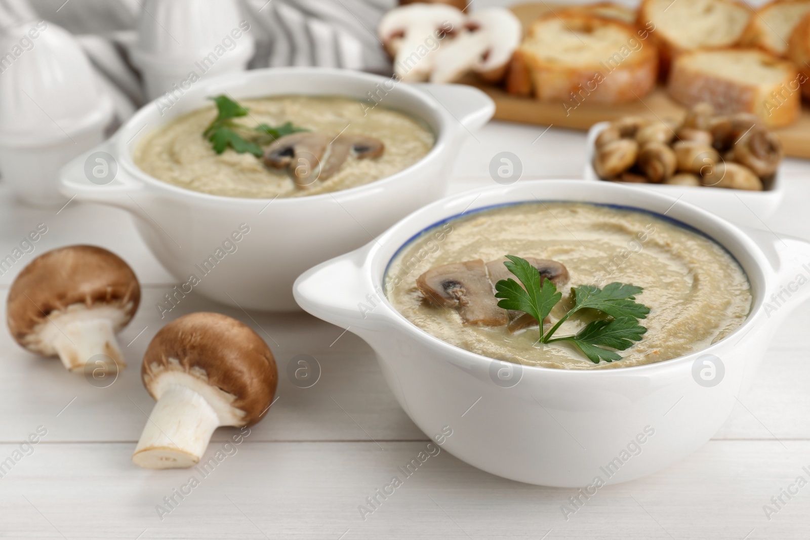 Photo of Delicious mushroom cream soup with parsley on white wooden table