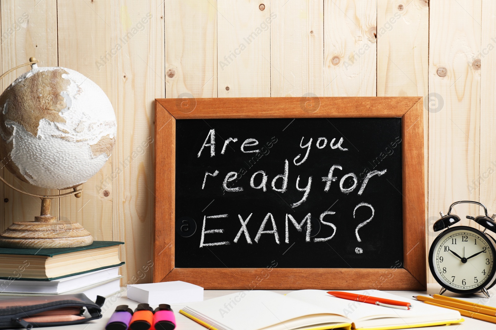 Photo of Blackboard with question Are You Ready For Exams? on white table near wooden wall