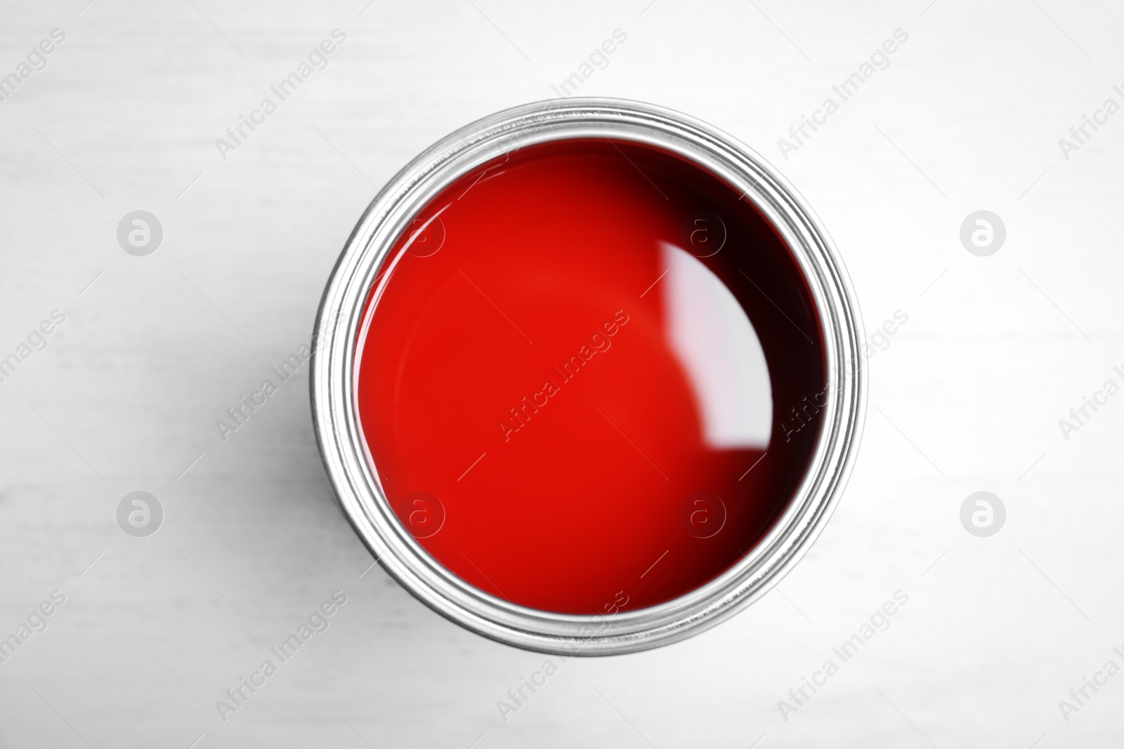 Photo of Can with red paint on wooden background, top view