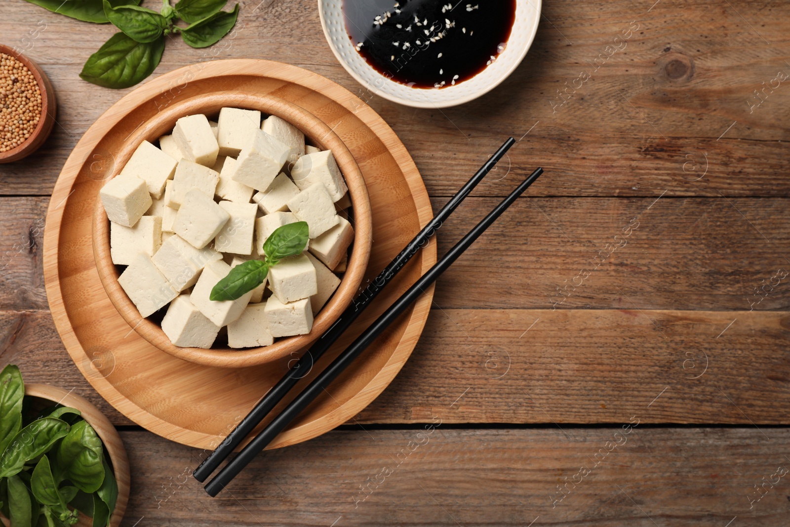 Photo of Delicious tofu with basil served on wooden table, flat lay. Space for text