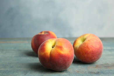 Photo of Fresh juicy peaches on wooden table against blue background, space for text