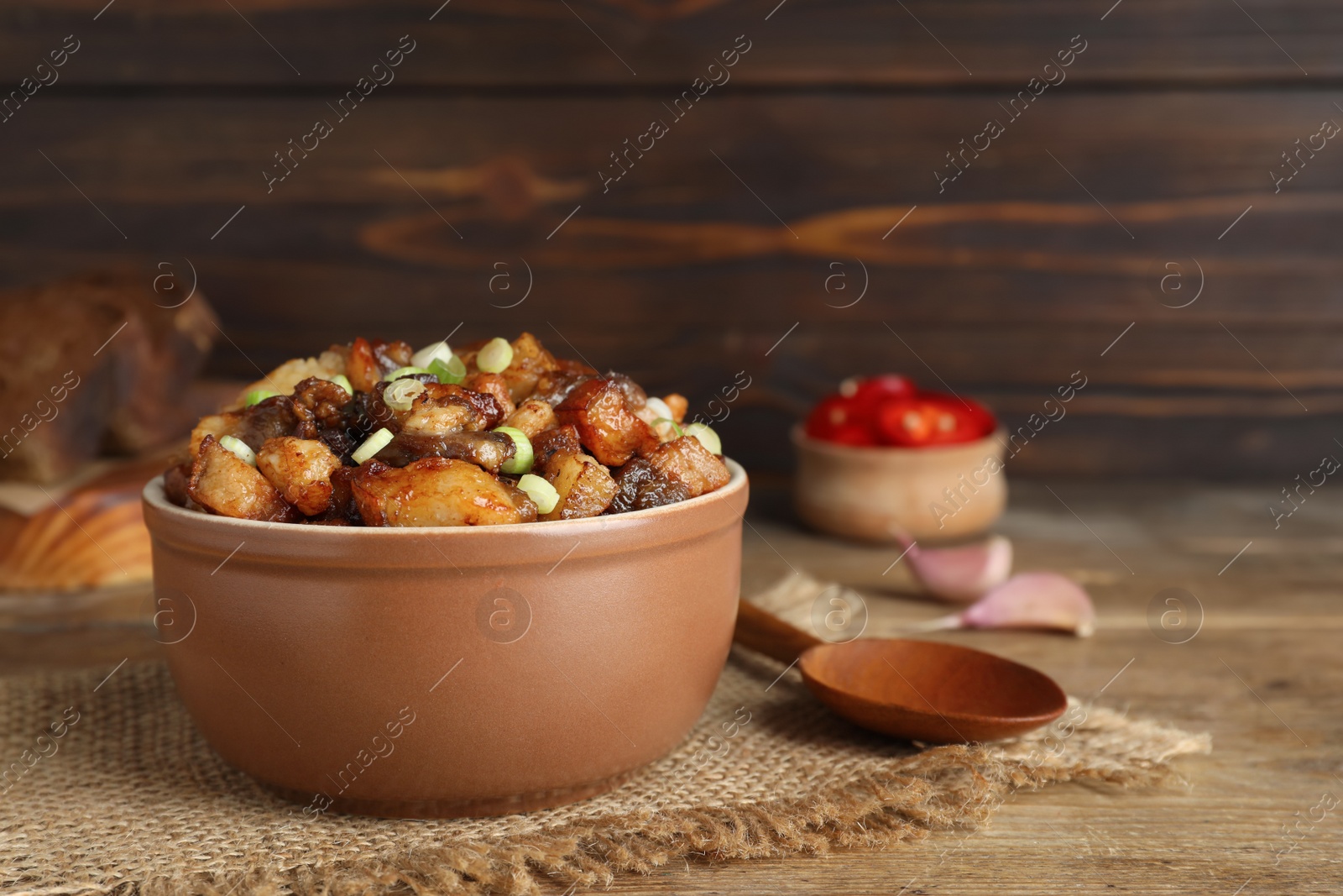 Photo of Tasty fried cracklings on wooden table, space for text. Cooked pork lard