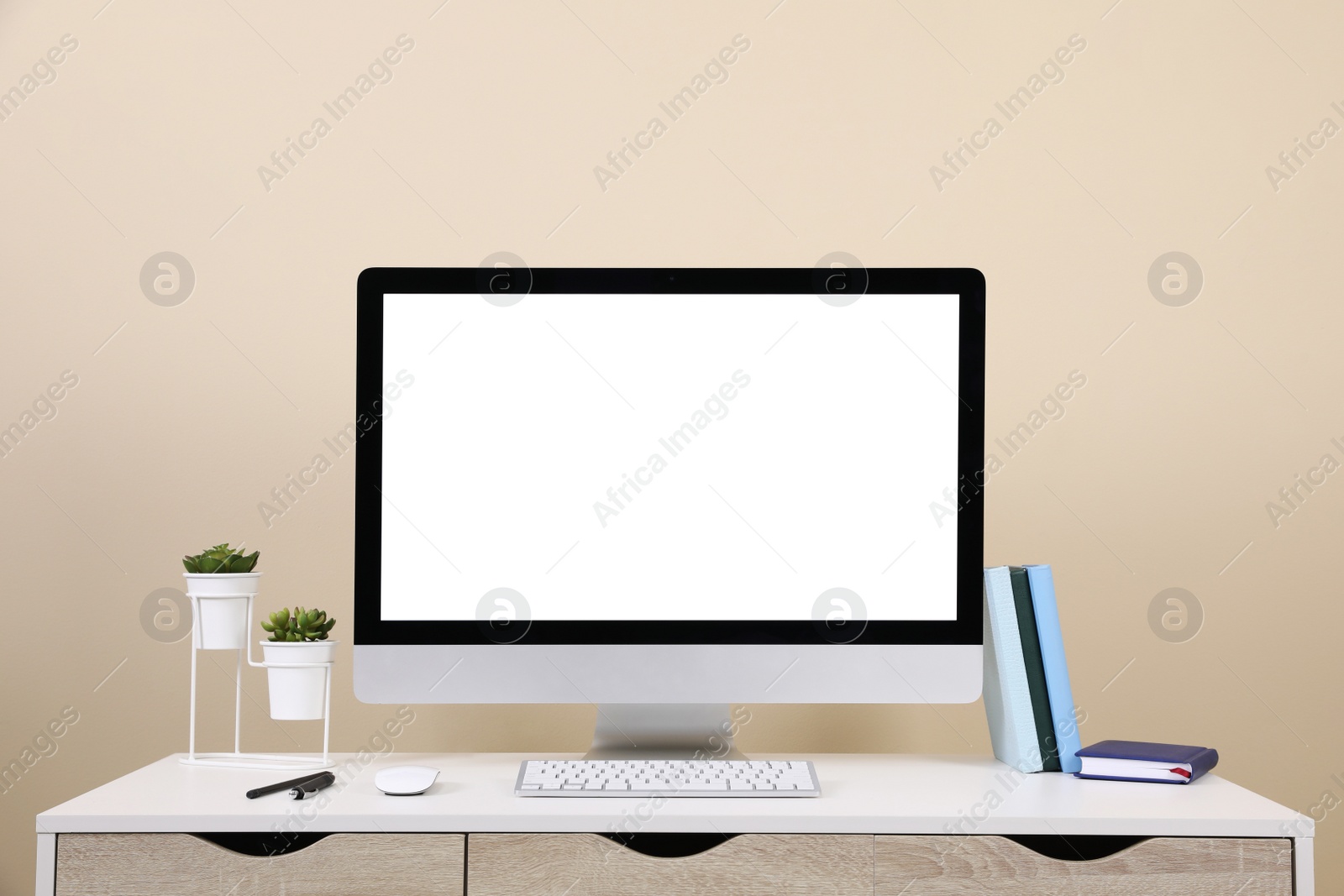 Photo of Comfortable workplace with blank computer display on desk near beige wall. Space for text