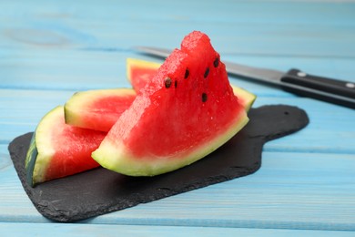 Photo of Slate board with slices of juicy watermelon on light blue wooden table