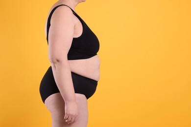 Photo of Overweight woman in underwear on orange background, closeup. Space for text