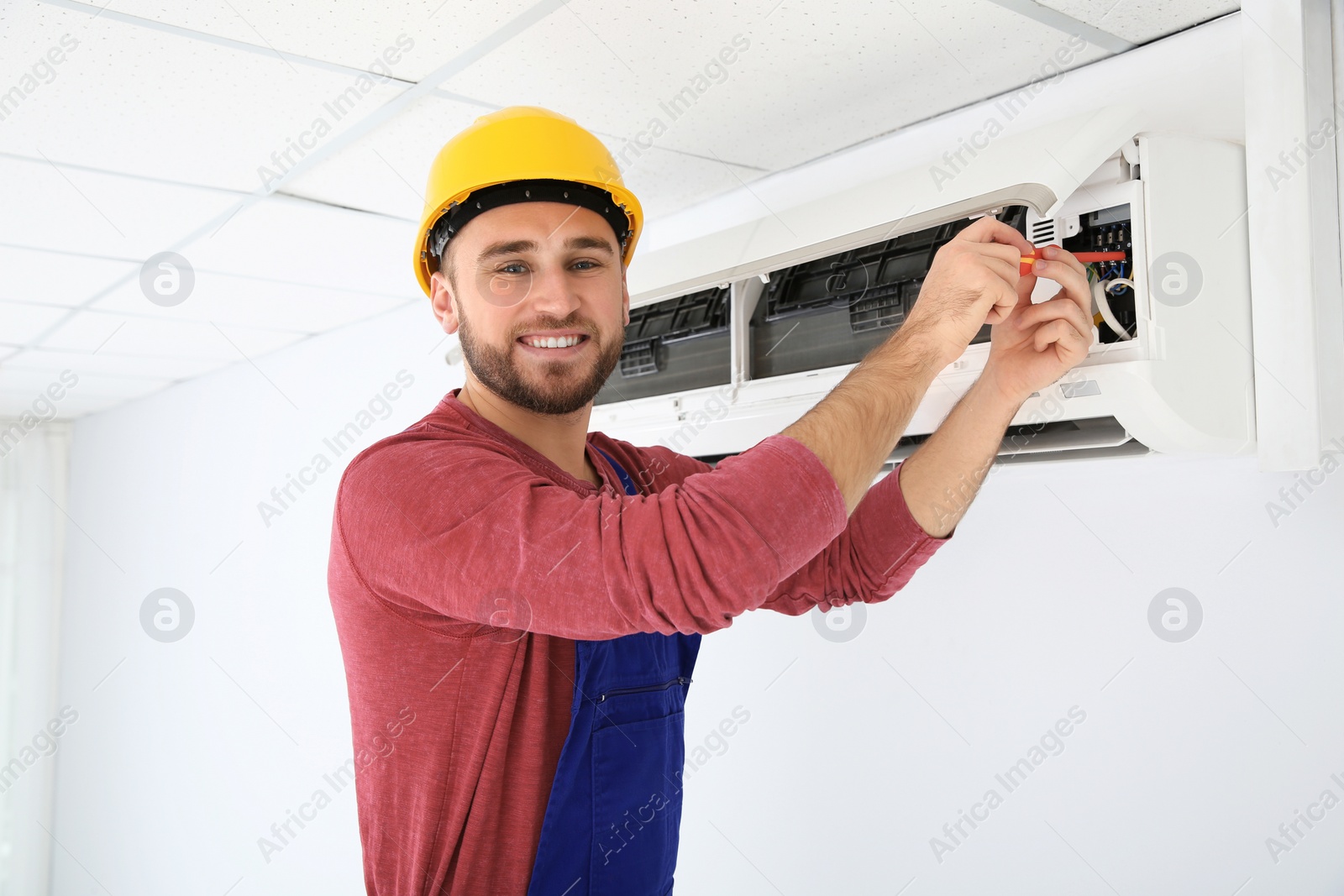 Photo of Electrician with screwdriver repairing air conditioner indoors