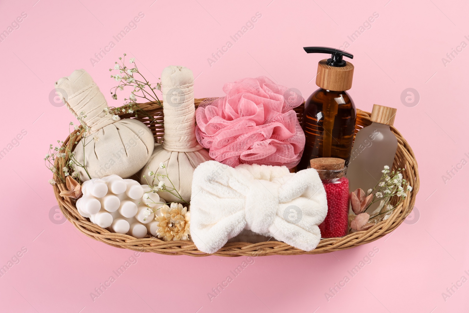 Photo of Spa gift set with different products in wicker basket on pink background, top view