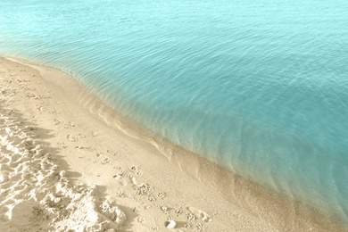 View of sea water and beach sand on sunny summer day