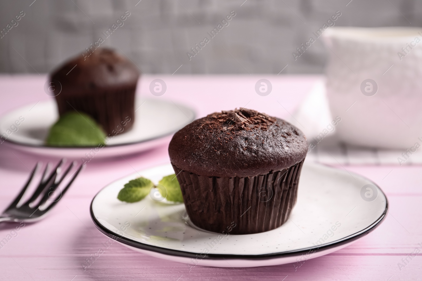 Photo of Delicious chocolate muffin served on pink wooden table