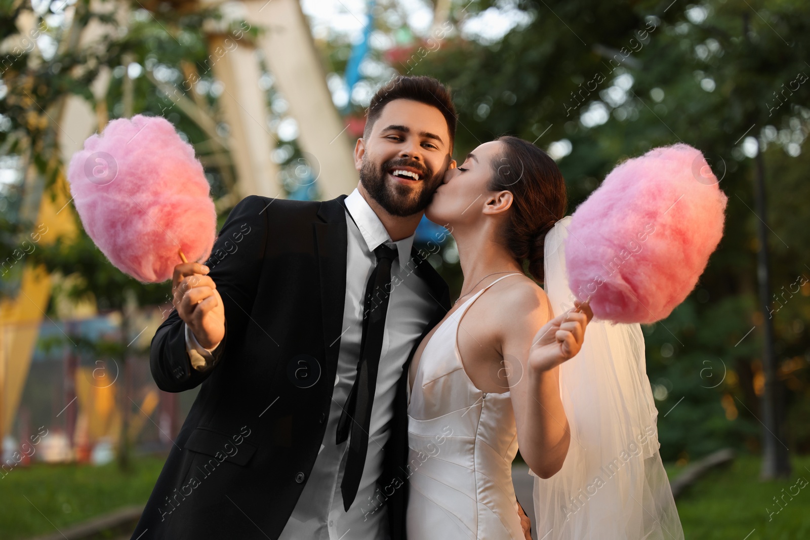 Photo of Happy newlywed couple with cotton candies outdoors