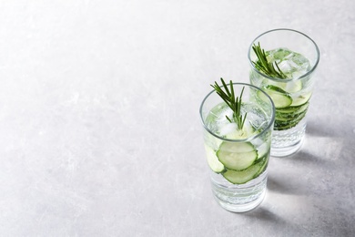 Photo of Glasses of fresh cucumber water on grey background. Space for text
