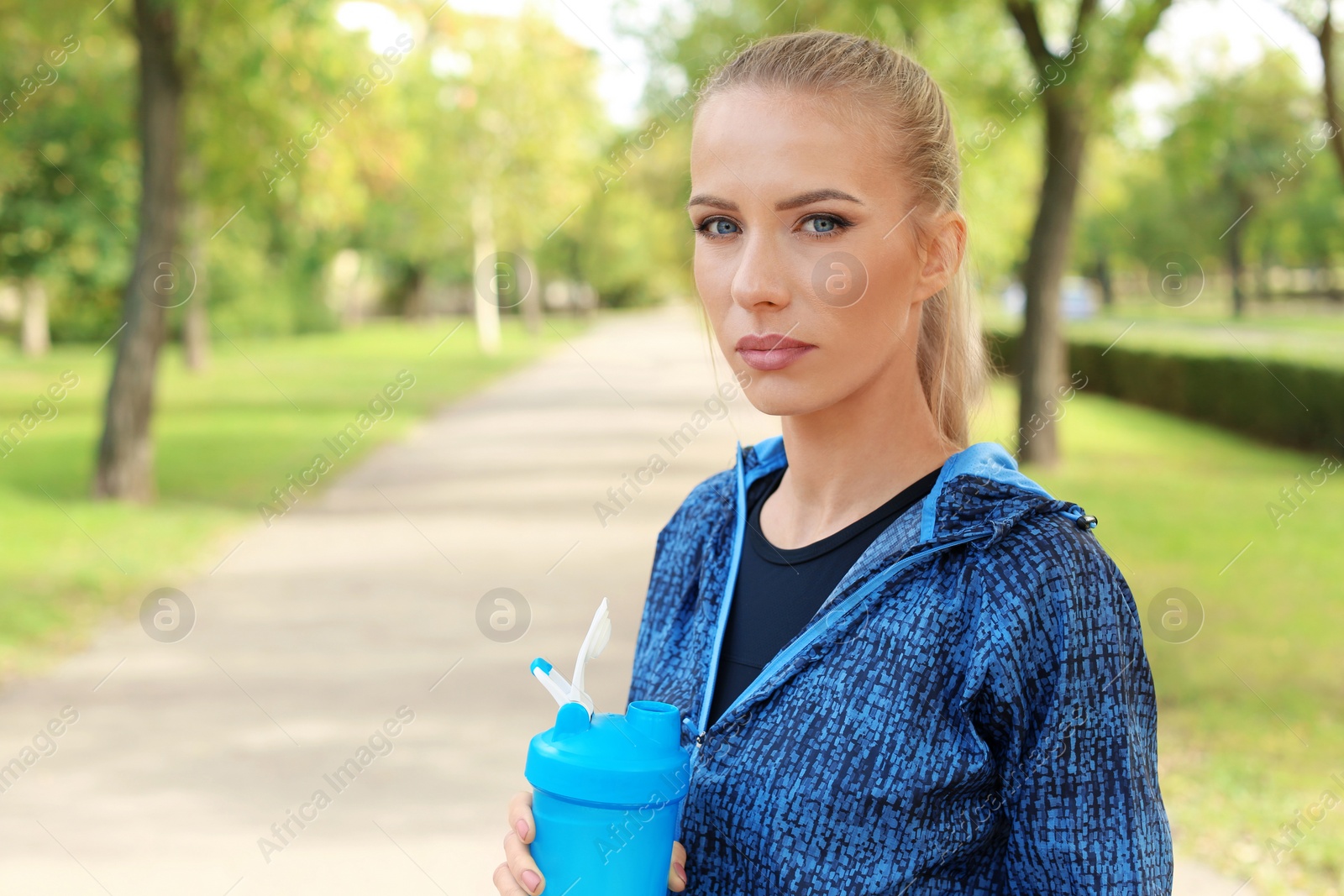 Photo of Woman with bottle of protein shake in park. Space for text