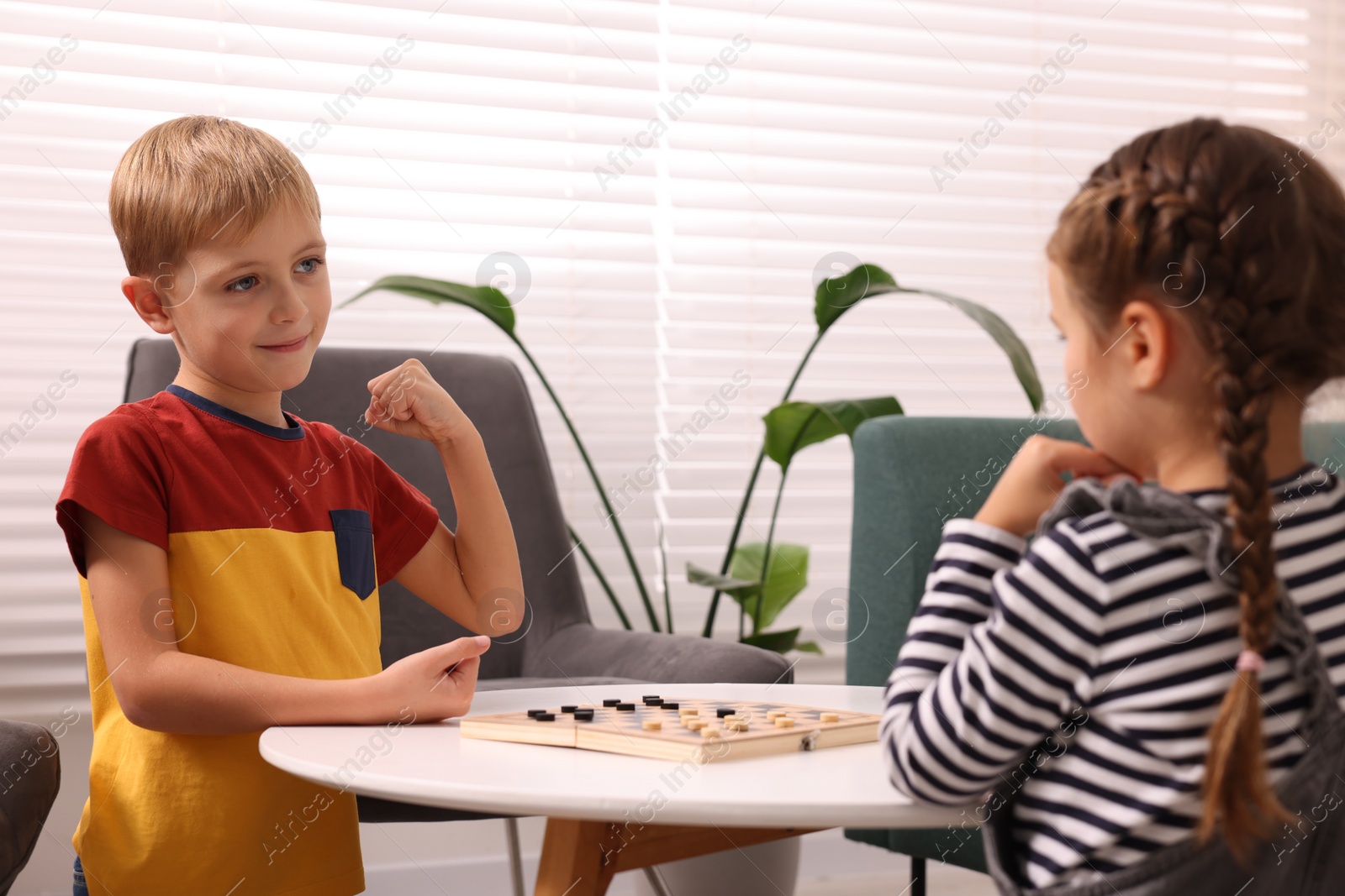 Photo of Children playing checkers at coffee table indoors