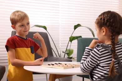 Photo of Children playing checkers at coffee table indoors