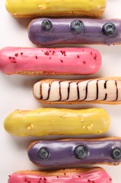 Delicious eclairs covered with glaze on white background, top view