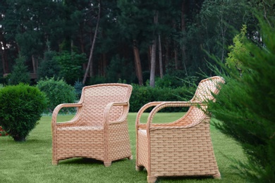 Garden rattan armchairs on green grass at backyard