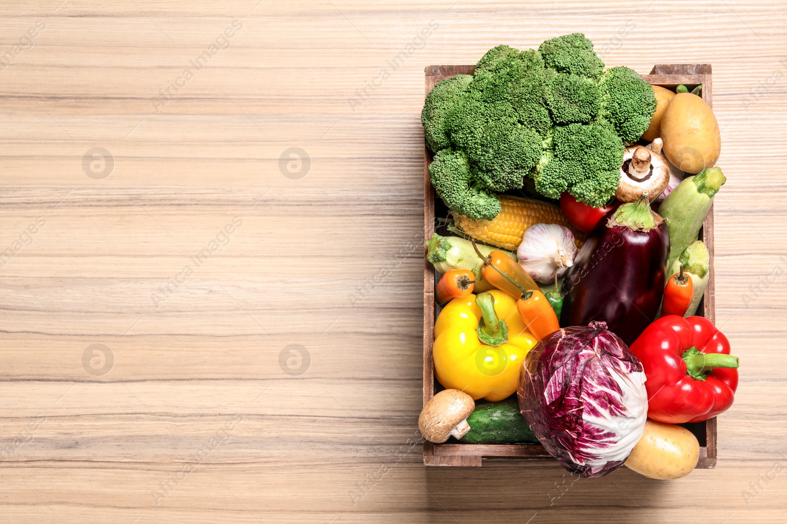 Photo of Crate with different fresh vegetables on wooden background, top view. Space for text