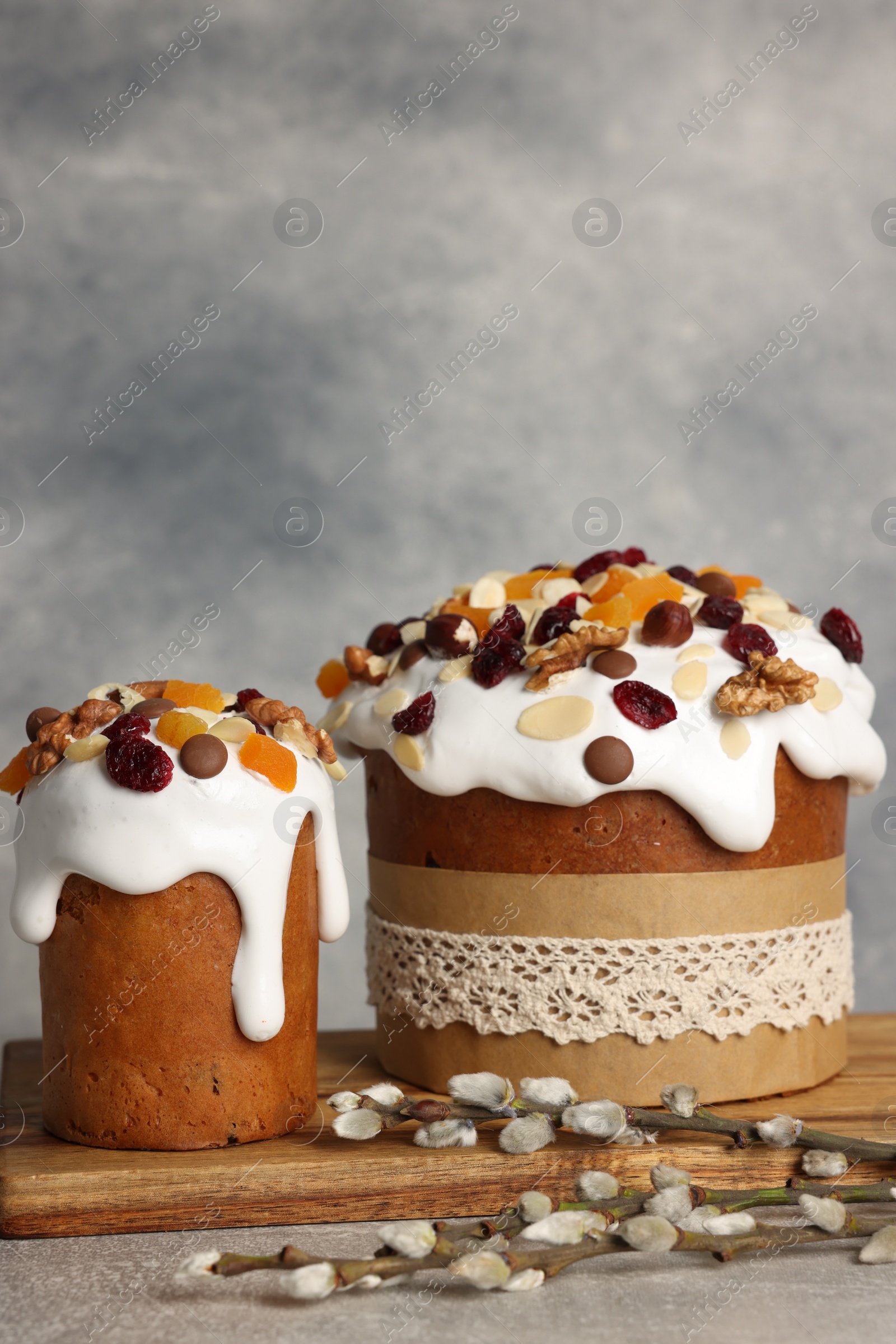 Photo of Tasty Easter cakes and willow branches on grey table