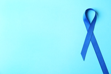 Blue ribbon on color background, top view with space for text. Colon cancer awareness concept