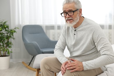 Arthritis symptoms. Man suffering from pain in knee at home