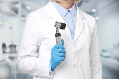 Image of Professional dermatologist with dermatoscope on blurred background, closeup