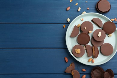 Flat lay composition with delicious peanut butter cups on blue wooden table, space for text