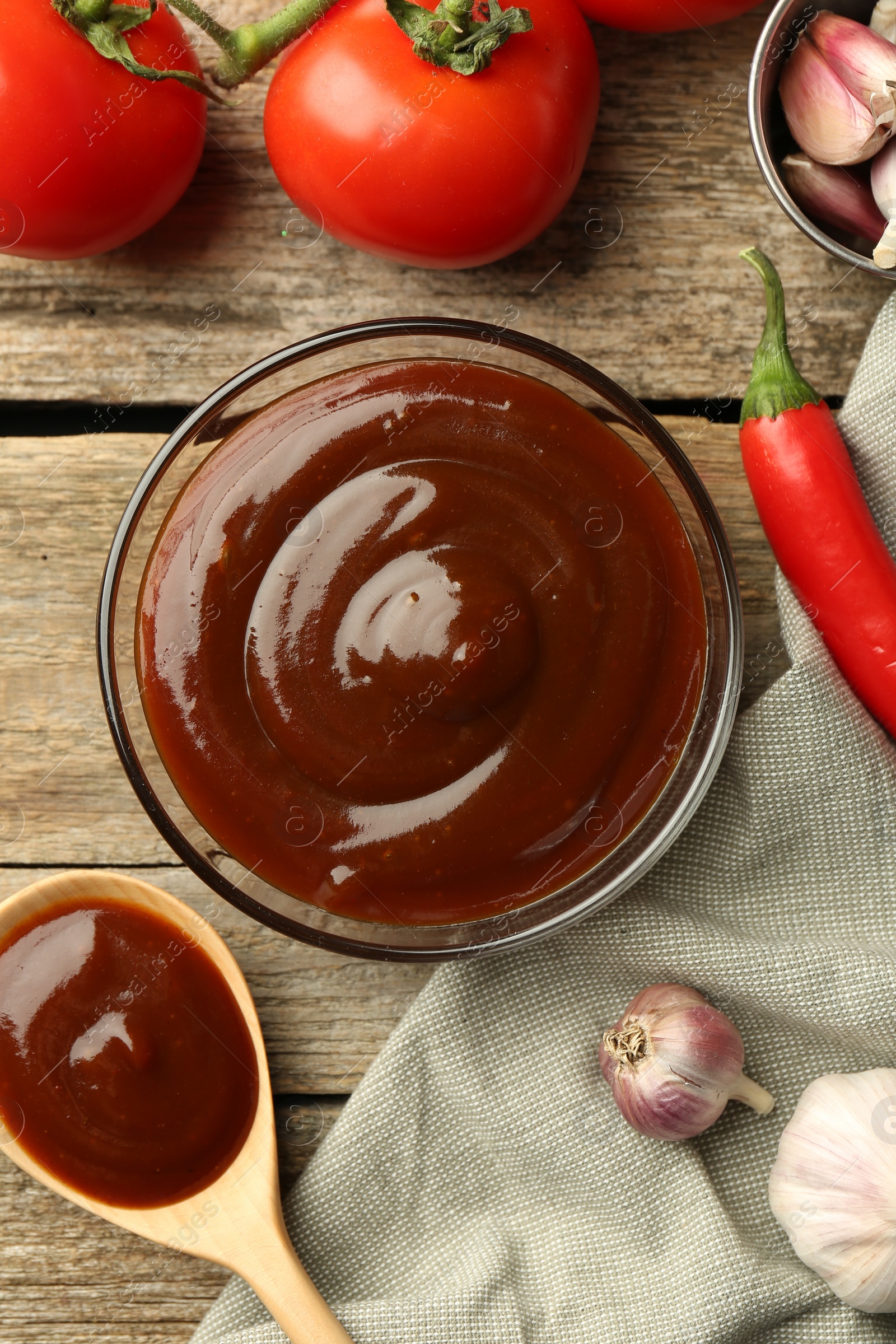 Photo of Flat lay composition with tasty barbeque sauce in bowl on wooden table