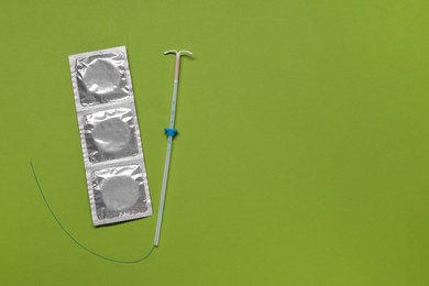 Photo of Contraception choice. Condoms and intrauterine device on green background, flat lay. Space for text