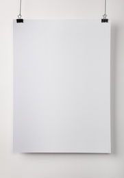 Photo of White blank poster hanging near light wall