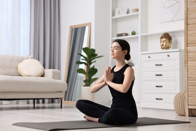 Beautiful girl meditating on yoga mat at home