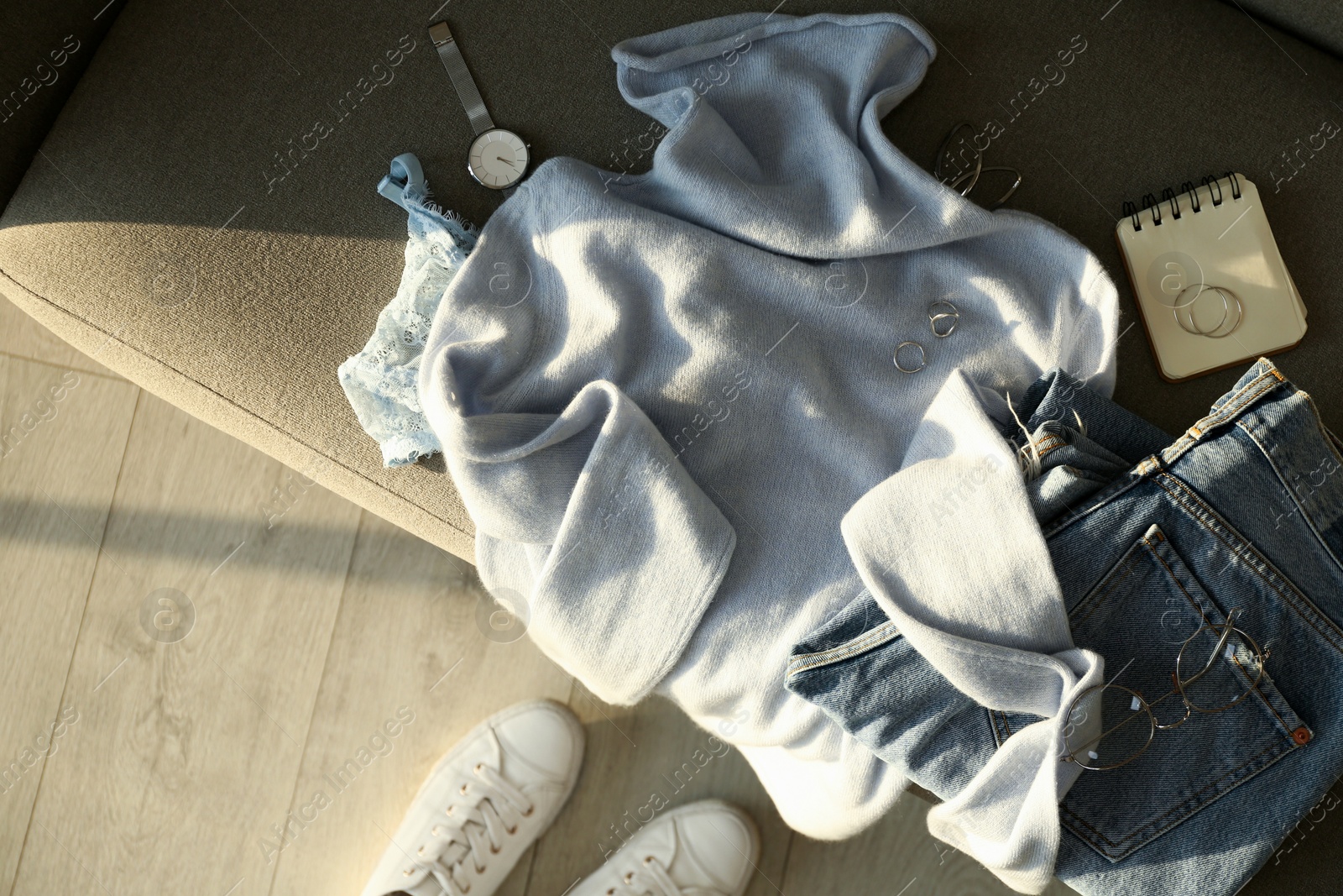 Photo of Soft cashmere sweater, jeans and accessories on sofa, flat lay