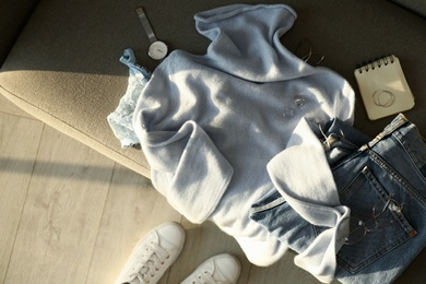 Photo of Soft cashmere sweater, jeans and accessories on sofa, flat lay