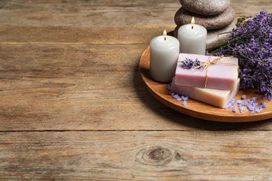 Burning candles, stones, soap bars and lavender flowers on wooden table. Space for text