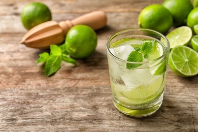 Photo of Refreshing beverage with mint and lime in glass on table