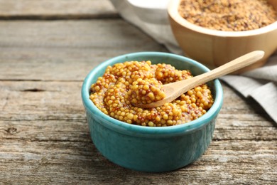 Photo of Whole grain mustard in bowl and spoon on wooden table