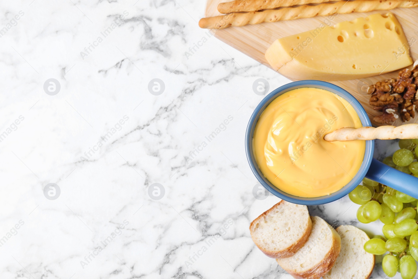 Photo of Flat lay composition with pot of delicious cheese fondue on marble table, space for text