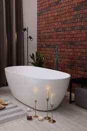 Photo of Stylish bathroom interior with ceramic tub and burning candles