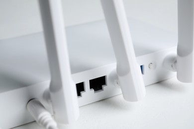 Photo of New modern Wi-Fi router on white table, closeup