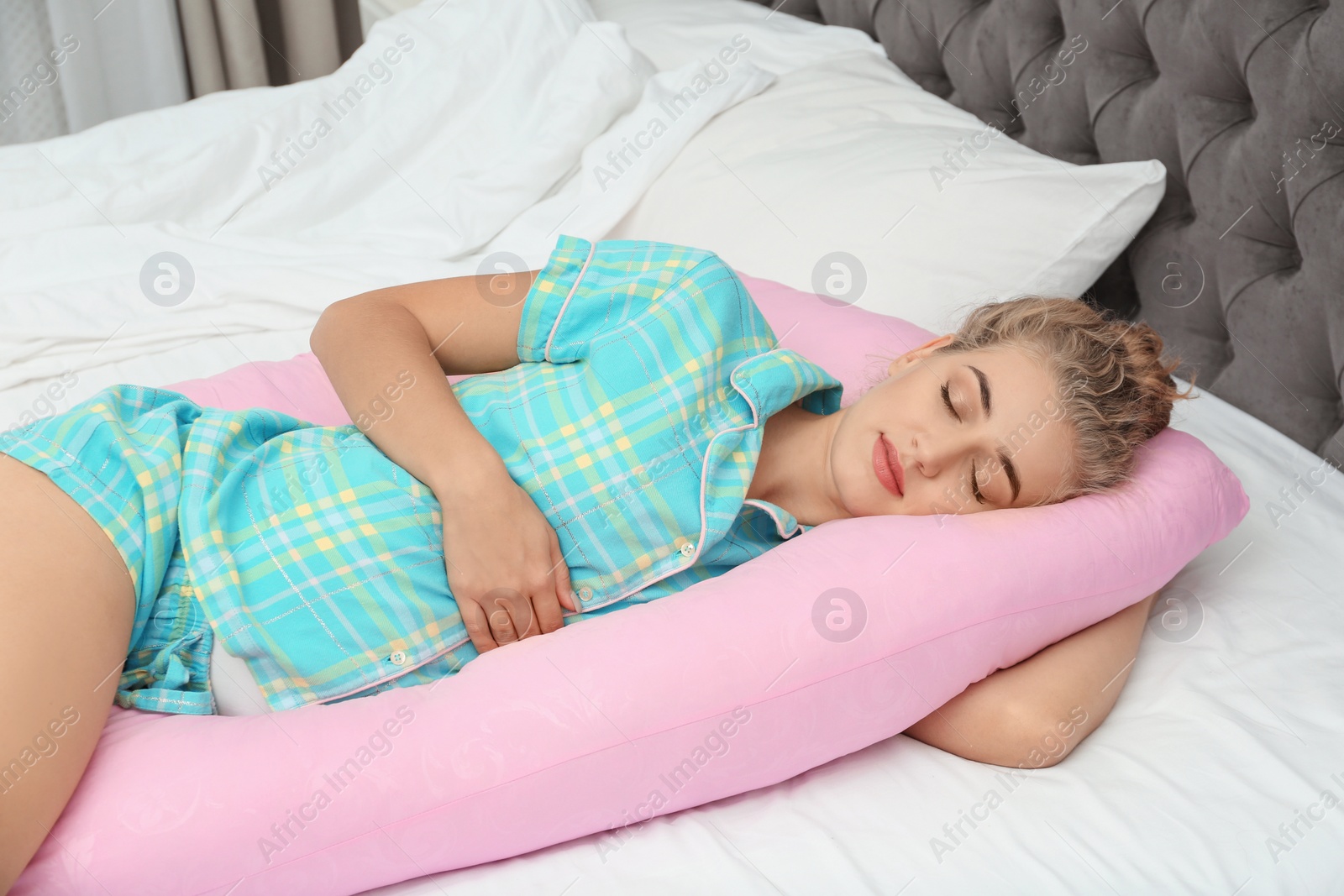 Photo of Beautiful pregnant woman sleeping with maternity pillow on bed at home