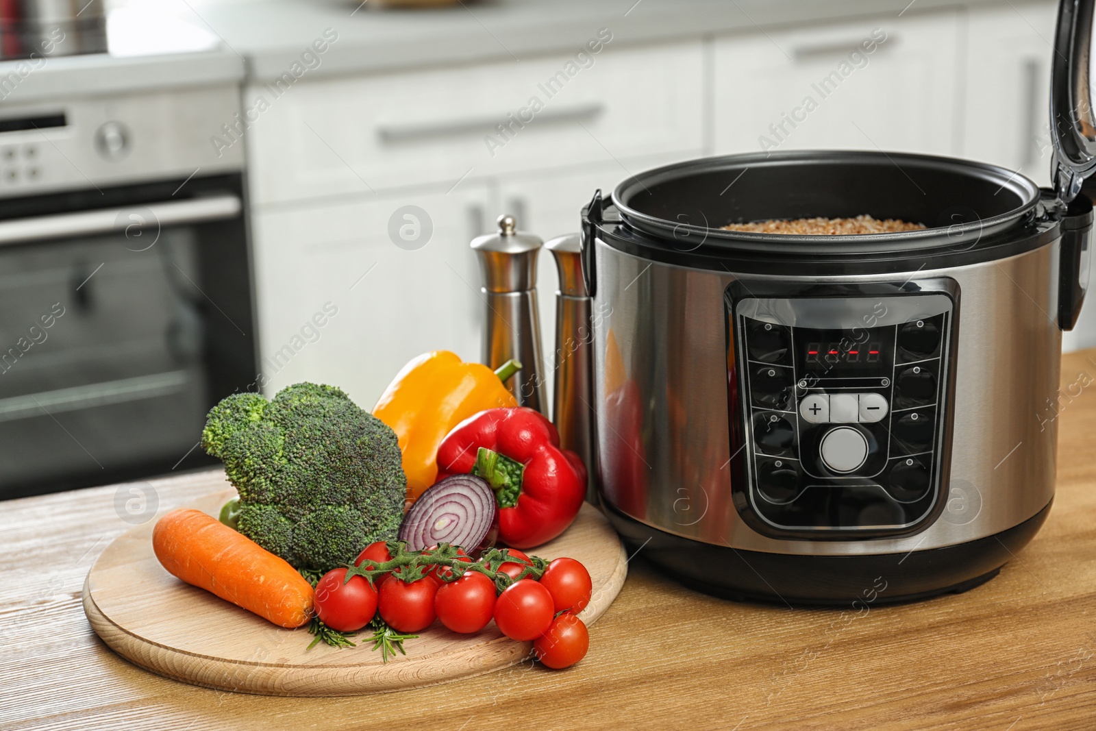 Photo of Delicious buckwheat in modern multi cooker and products on wooden table. Space for text