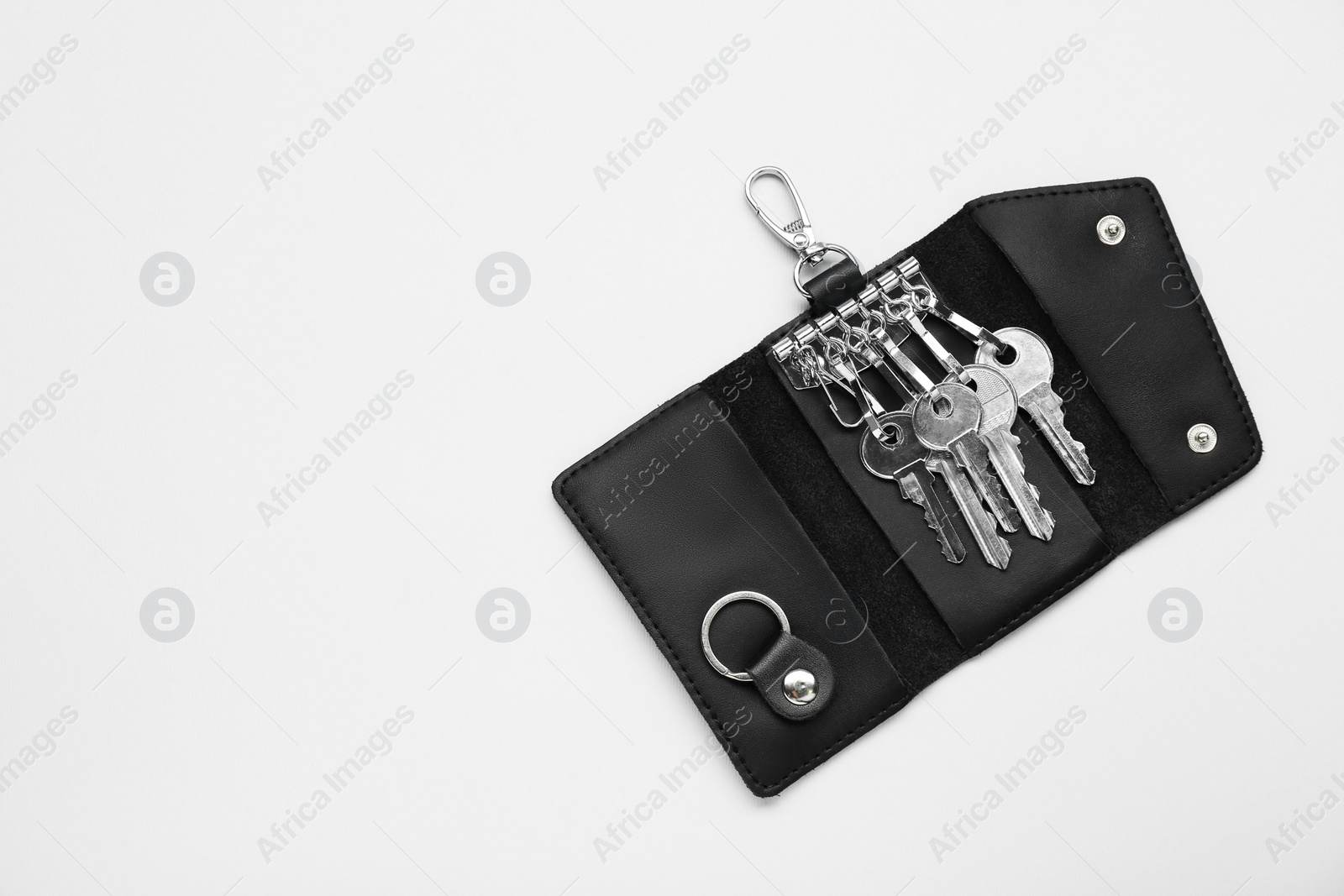 Photo of Open leather holder with keys on light grey background, top view. Space for text