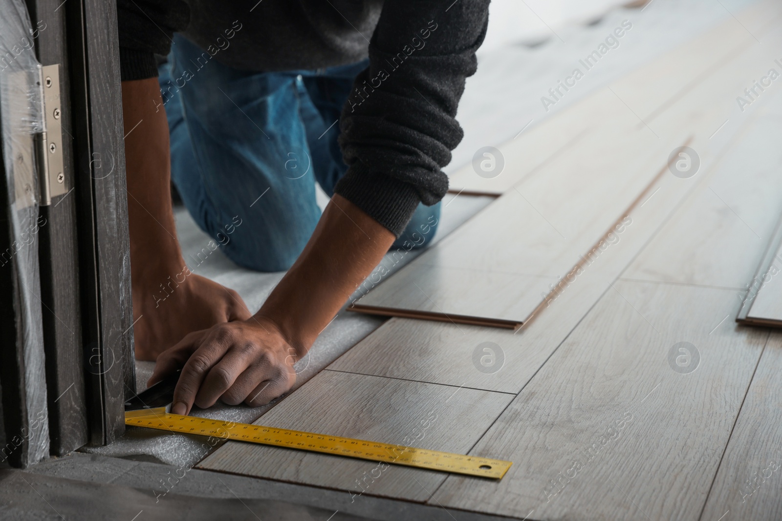 Photo of Worker installing new laminate flooring in room, closeup